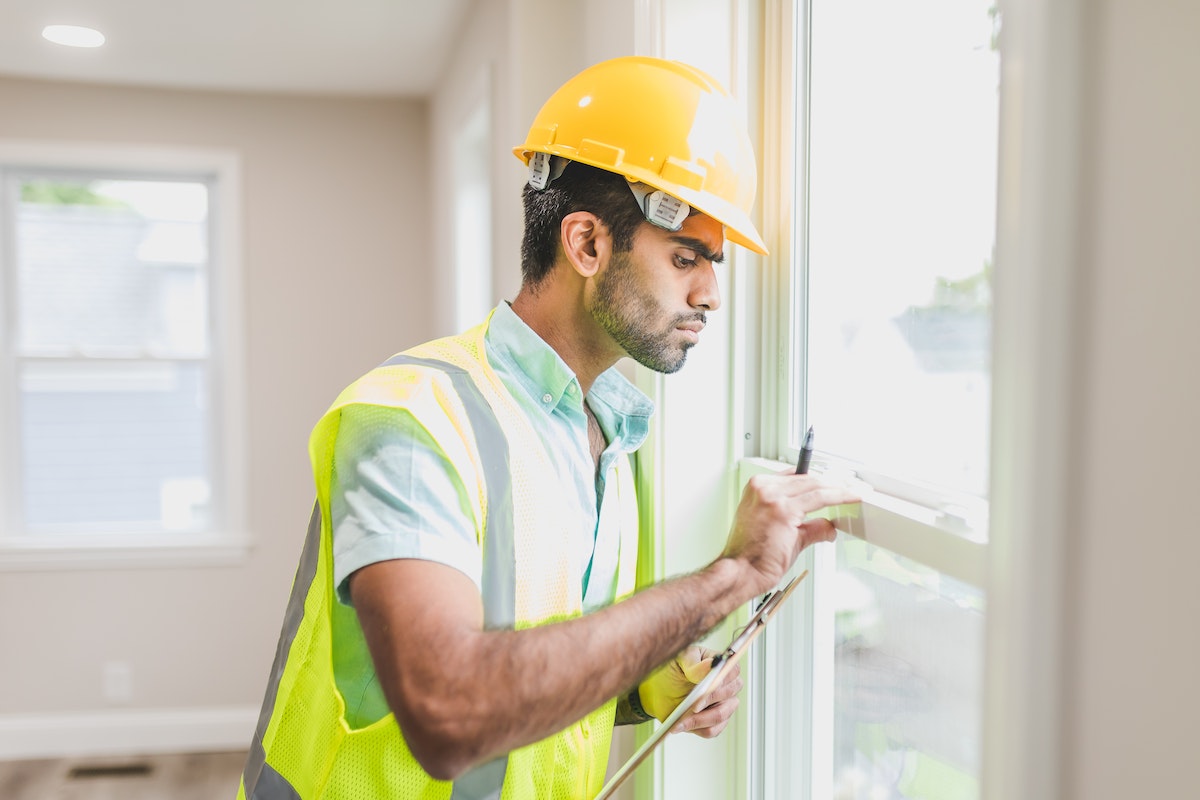 construction-worker-in-yellow-safety-vest-and-helmet-checking-glass-window-of-a-house